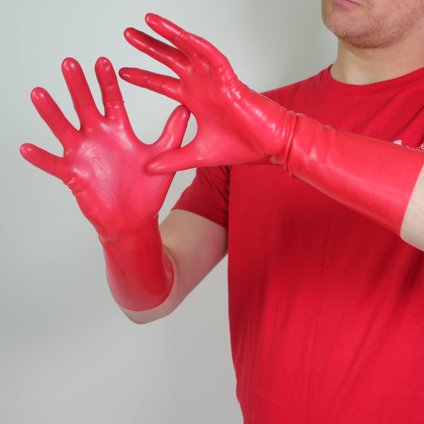 Person wearing red rubber gloves and a red shirt against a plain background